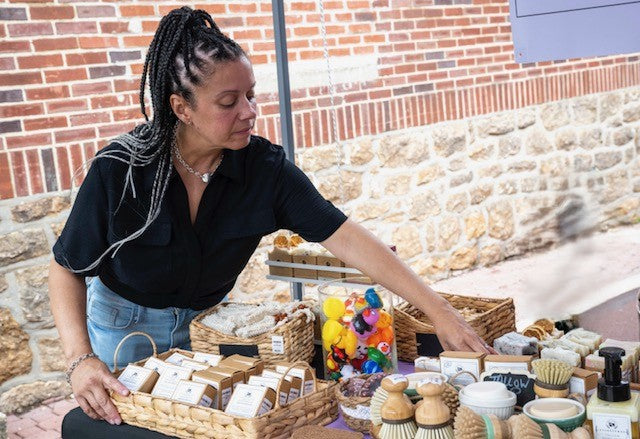Woman at an outdoor market booth selling tallow products