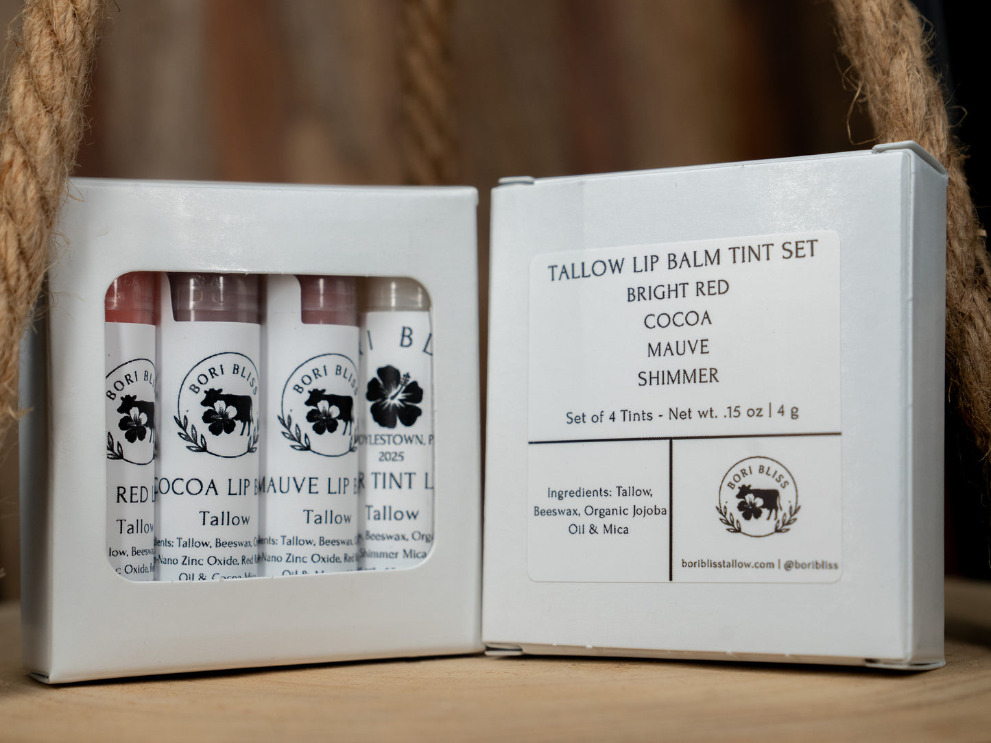 Set of four Bori Bliss tallow tinted lip balm tubes in a white box with branding and product details. Bright red, cocoa, mauve, and shimmer.